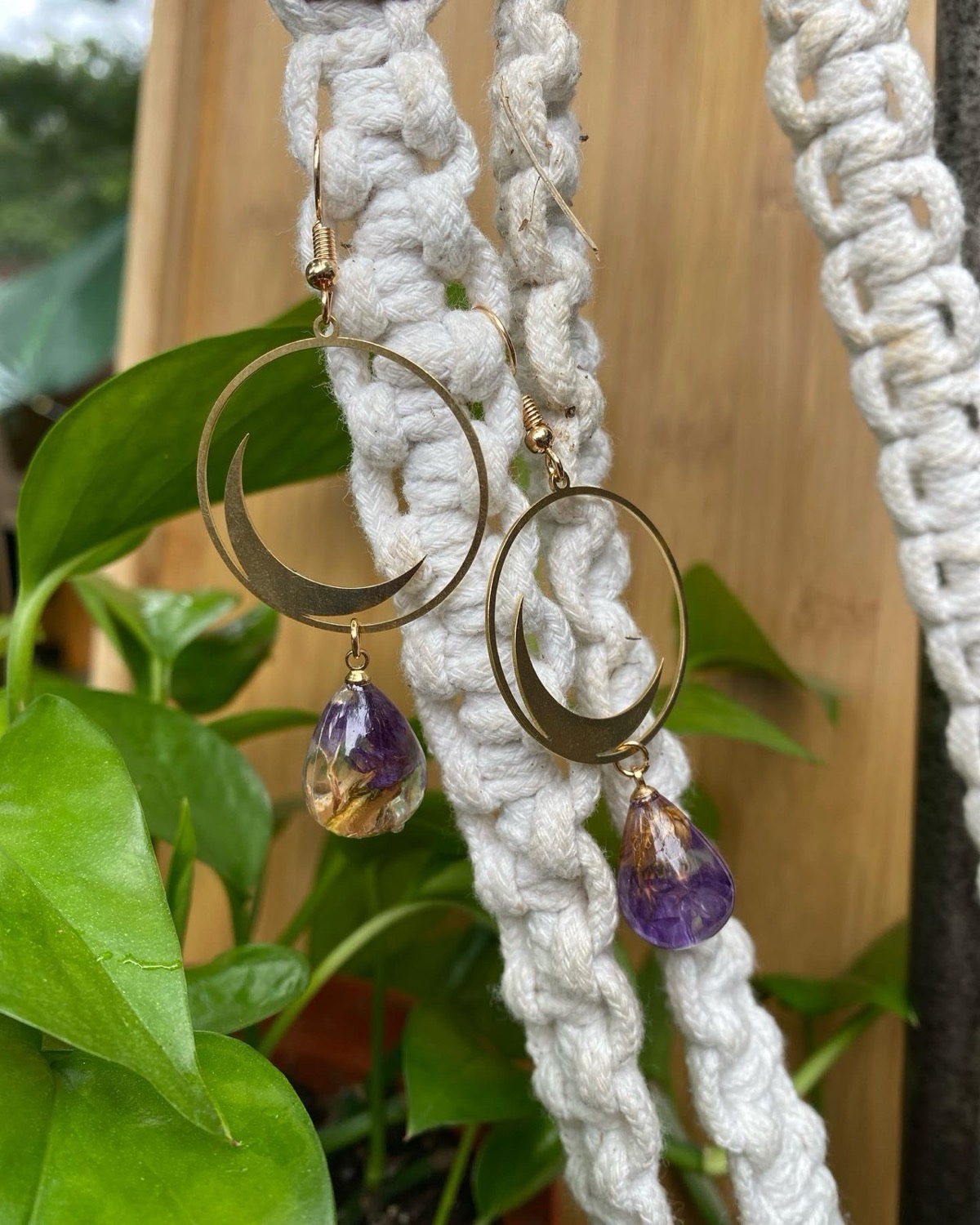 Amethyst and dried-flower resin drops hung beneath brass crescent moons
